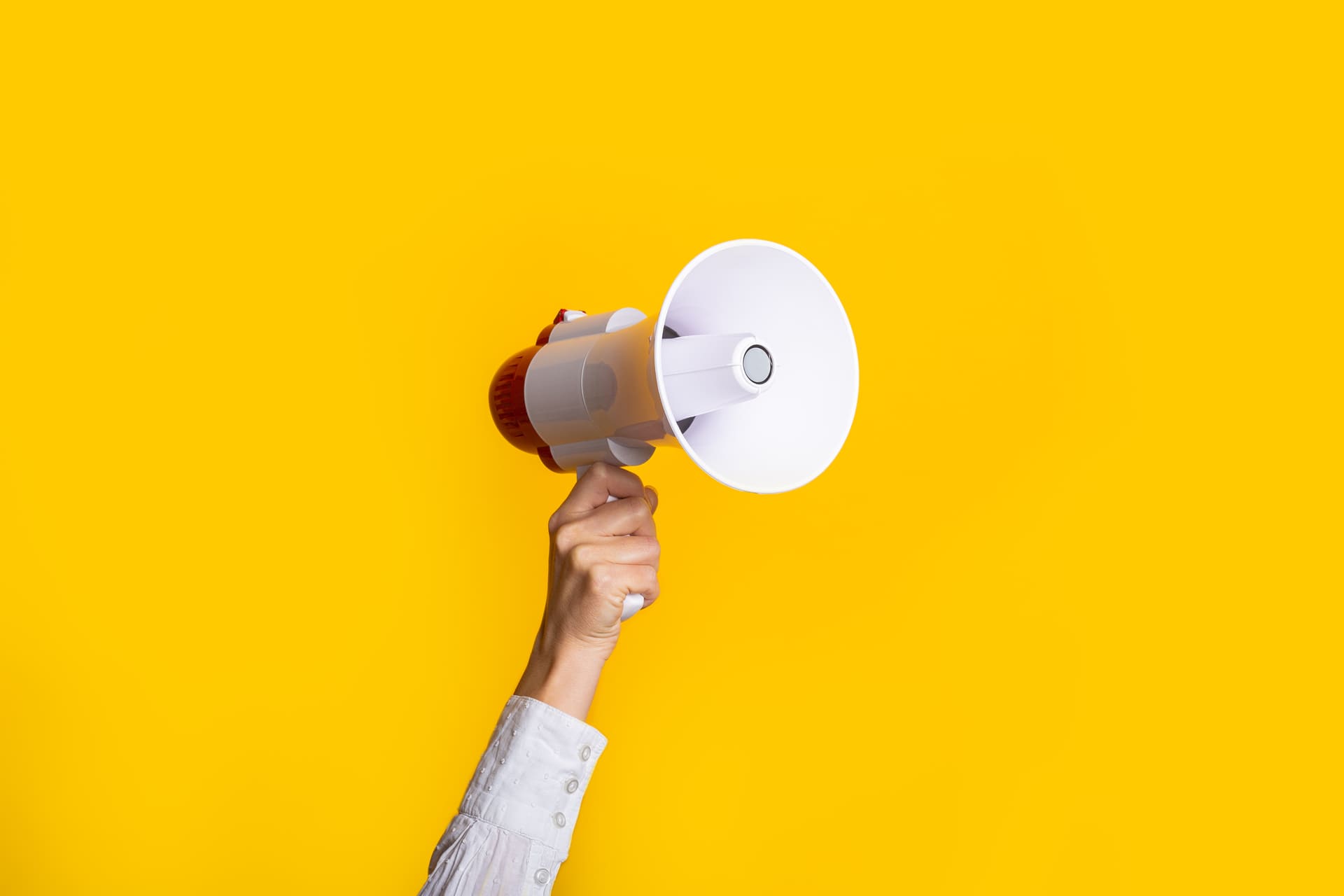 female-hand-holds-white-megaphone-yellow-background